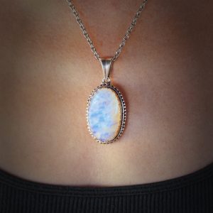 Opal gem stone on silver pendant. Selective focus.Added vignetting.