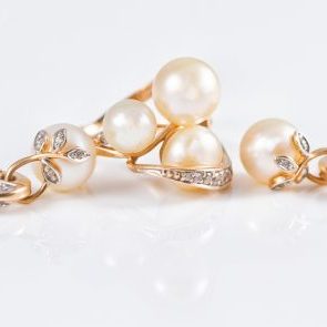 Elegant gold rings and gold earrings with pearls reflected in a white surface